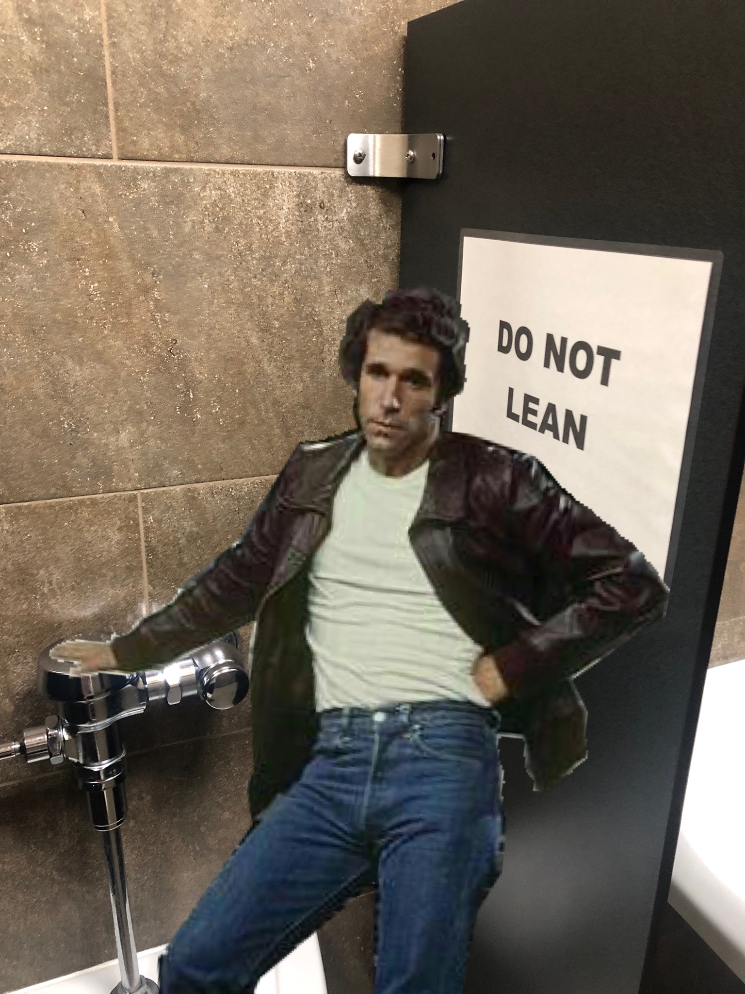 A black partition board with a paper sign attached that says "Do Not Lean," with the Fonz Leaning on it.